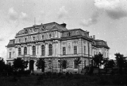 Das Foto zeigt ein mehrstöckiges Gebäude mit klassizistischer Fassade und reich verziertem Mansarddach. Die Architektur mit Säulen, Balkonen und ornamentaler Gestaltung deutet auf ein offizielles oder administratives Gebäude im österreichisch-ungarischen Einflussbereich hin.