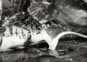 Das Bild zeigt die Überreste eines zerstörten Heckgeschützes auf einem Kriegsschiff mit stark deformierten Metallteilen und Trümmern. Die schweren Beschädigungen lassen auf Kampfeinwirkung oder Explosion schließen.