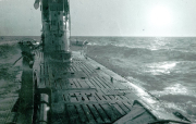 Aufnahme vom Deck eines deutschen U-Bootes bei bewegter See während des Ersten Weltkriegs. Das Holzdeck mit charakteristischen Planken und der Kommandoturm sind bei starkem Seegang zu sehen.