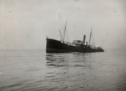 Ein Dampfschiff mit Schornstein und Segeltakelung fährt bei ruhiger See. Das Schiff zeigt die typische Bauweise eines Handelsschiffes aus der Zeit des Ersten Weltkriegs.
