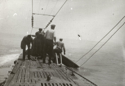 Mehrere Matrosen der Kaiserlichen Marine arbeiten auf dem Holzdeck eines U-Bootes bei ruhiger See. Die Aufnahme zeigt die typischen Deckarbeiten während einer Fahrt im Ersten Weltkrieg.