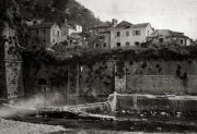 Blick auf einen mediterranen Küstenort mit mehrstöckigen Wohnhäusern oberhalb einer Steinmauer am Wasser. Die Aufnahme zeigt die typische Architektur eines adriatischen Hafenortes während des Ersten Weltkriegs.