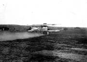 Ein deutsches Militärflugzeug steht auf einem Flugplatz mit mehreren Hangars im Hintergrund. Die Aufnahme zeigt die militärische Luftfahrt der Kaiserlichen Marine während des Ersten Weltkriegs.