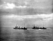 Drei Kriegsschiffe fahren in Formation auf ruhiger See unter bewölktem Himmel. Die Schiffe zeigen die charakteristische Silhouette von Kreuzern oder größeren Torpedobooten mit mehreren Schornsteinen und Masten.