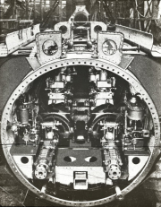 Die Aufnahme zeigt den Maschinenraum eines deutschen U-Bootes mit dem Dieselmotor und der technischen Ausrüstung. Der kreisrunde Querschnitt des Druckkörpers mit den charakteristischen Spanten und der komplexen Maschinentechnik ist deutlich erkennbar.