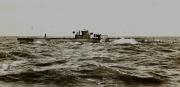 Ein deutsches U-Boot der Kaiserlichen Marine fährt aufgetaucht durch bewegte See. Auf dem Turm und Deck sind mehrere Besatzungsmitglieder zu erkennen.