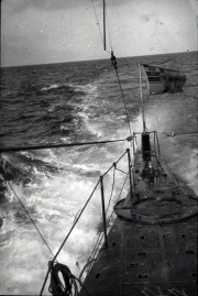 Das deutsche U-Boot S.M. U 39 fährt bei schwerem Seegang an der Oberfläche, wobei die Wellen über das Vordeck schlagen. Die Aufnahme zeigt den Turm mit Periskop und die typische Silhouette eines kaiserlichen U-Boots der U 31-Klasse.
