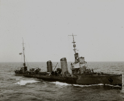 Ein deutsches Torpedoboot mit charakteristischen Schornsteinen und Aufbauten fährt bei mäßigem Seegang. Die Besatzung ist an Deck zu erkennen, während das Schiff unter Dampf steht.