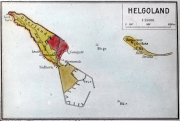 Die Karte zeigt die strategisch wichtige Nordseeinsel Helgoland mit der Hauptinsel und der vorgelagerten Düne. Verschiedene militärische Bereiche sind farblich markiert, darunter Kommandantur, Leuchtturm und Hafenanlagen.