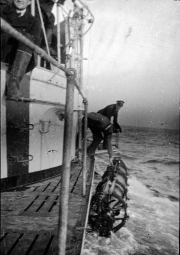 Mehrere Matrosen arbeiten bei starkem Seegang an Deck eines U-Bootes, während Wasser über das Deck spült. Die Aufnahme zeigt die gefährlichen Arbeitsbedingungen der U-Boot-Besatzungen während des Ersten Weltkriegs.