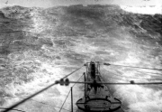 Aufnahme vom Kommandoturm eines U-Bootes bei schwerem Seegang mit hohen Wellen. Das Vorderdeck und die Bugsektion sind bei den extremen Wetterbedingungen sichtbar.