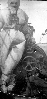 Ein Matrose der Kaiserlichen Marine trägt eine Tauchretter-Ausrüstung mit Atemschutzgerät und sitzt an Deck eines U-Bootes. Die Aufnahme zeigt die Sicherheitsausrüstung für Notfälle unter Wasser während des Ersten Weltkriegs.