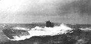 Ein deutsches U-Boot kämpft sich durch hohe Wellen und schweren Seegang. Das Fahrzeug ist teilweise von Gischt und Spritzwasser umhüllt, während es an der Oberfläche fährt.