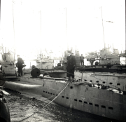 Mehrere deutsche U-Boote liegen nebeneinander in einem Hafen, wobei Besatzungsmitglieder auf den Decks und Türmen zu sehen sind. Die Aufnahme zeigt die charakteristischen Rümpfe und Aufbauten der Unterseeboote der Kaiserlichen Marine.