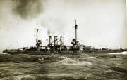Ein deutsches Schlachtschiff der Helgoland-Klasse fährt bei bewegter See unter Dampf. Das Kriegsschiff zeigt die charakteristische Silhouette mit vier Schornsteinen und schwerer Artillerie-Bewaffnung.
