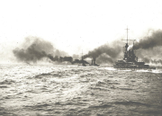Mehrere deutsche Großkampfschiffe fahren in Formation auf bewegter See und erzeugen dabei starke Rauchsäulen aus ihren Schornsteinen. Die Aufnahme zeigt die charakteristische Silhouette von Schlachtschiffen mit ihren markanten Aufbauten und Geschütztürmen.