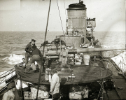 Das Torpedoboot G 92 zeigt seine Besatzung bei der Bedienung des Heckgeschützes während einer Fahrt auf See. Die Aufnahme dokumentiert die Geschützbedienung und den Aufbau des Kriegsschiffes im Ersten Weltkrieg.
