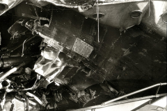 Die Aufnahme zeigt das völlig verwüstete Innere eines Kriegsschiffes mit verbogenen Metallteilen, Trümmern und zerstörten Aufbauten. Die schweren Schäden deuten auf Kampfeinwirkung oder Explosion hin.