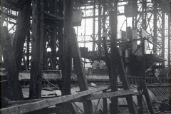Die Aufnahme zeigt das Innere einer Werft oder Fabrikhalle mit komplexer Stahlkonstruktion und verschiedenen Maschinenbauteilen. Durch die großen Fenster der Hallenkonstruktion fällt Tageslicht auf die industriellen Anlagen und Werkstücke.