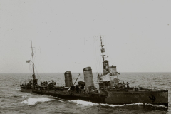 Ein deutsches Torpedoboot mit charakteristischen Schornsteinen und Aufbauten fährt bei mäßigem Seegang. Die Besatzung ist an Deck zu erkennen, während das Schiff unter Dampf steht.
