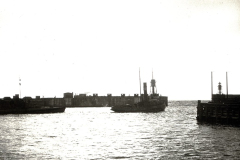 Ein Kriegsschiff mit charakteristischen Masten und Schornstein liegt zwischen zwei Hafenmolen. Die Aufnahme entstand im Kontext der deutschen U-Boot-Operationen im Mittelmeer während des Ersten Weltkriegs.