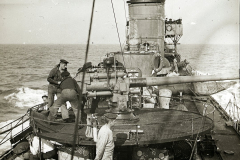 Das Torpedoboot G 92 zeigt seine Besatzung bei der Bedienung des Heckgeschützes während einer Fahrt auf See. Die Aufnahme dokumentiert die Geschützbedienung und den Aufbau des Kriegsschiffes im Ersten Weltkrieg.