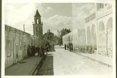Straßenszene in nordafrikanischer Stadt mit Kirchturm und Zivilbevölkerung