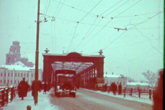 Straßenszene in Russland mit rotem Holzbau und Strommasten im Winter
