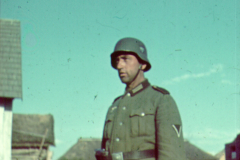 Deutscher Soldat in Uniform mit Stahlhelm in russischem Dorf