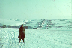 Frau in Winterlandschaft mit Blick auf russische Siedlung