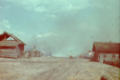 Russische Landstraße mit Holzgebäuden und Militärfahrzeug
