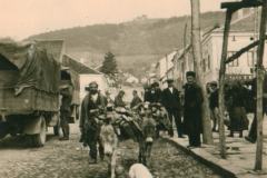 Straßenszene in einem Balkan-Dorf mit Pferdefuhrwerk und Zivilbevölkerung