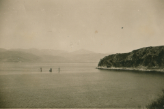 Seelandschaft mit bewaldeter Küste und Holzpfählen im Wasser, Balkan 1941-1943