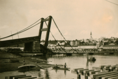 Hängebrücke über Fluss mit Stadtsilhouette im Hintergrund, Balkan 1941-1943
