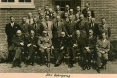 Gruppenfoto von Offizieren und Zivilpersonen vor Backsteingebäude, Beschriftung 'Der Lehrgang'