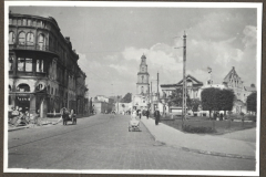 Stadtplatz mit Kirchturm und Kriegsschäden an Wohngebäude