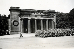 Militärische Parade vor klassizistischem Gebäude mit Hakenkreuzdekorationen