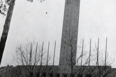 Kirchengeb?ude mit schlankem Turm und Laubbaum im Winter