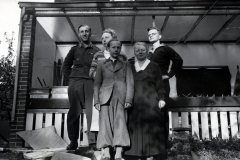 Gruppenfoto vor Wohnhaus mit Soldat und Zivilpersonen
