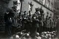 Britische Soldaten mit Stahlhelmen vor Backsteingebäude