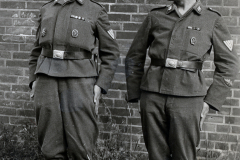Zwei Soldaten in Uniform vor Backsteinmauer