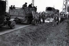 Militärischer Transportkonvoi mit Lastkraftwagen und Soldaten an Infrastrukturanlage