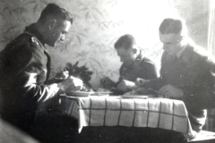Vier Soldaten bei Mahlzeit an Tisch in Innenraum