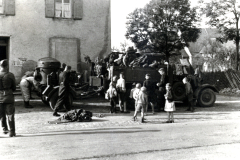 Militärischer Lastkraftwagen mit Zivilbevölkerung in Dorfstraße