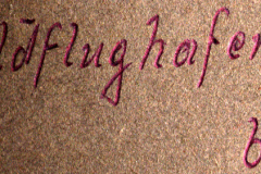 Handschriftliche Beschriftung 'Feldflughafen' auf Dokumentoberfläche
