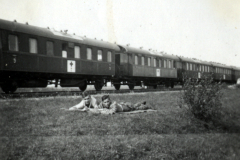 Zwei Soldaten im Gras neben Eisenbahnzug
