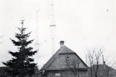 Holzhaus mit Ziegeldach und Funkturm im Hintergrund