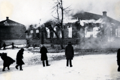 Brennende Holzgebäude mit Zivilisten im Schnee