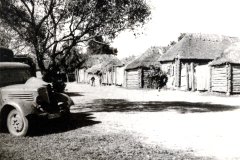 Dorfstraße mit Strohdachhäusern und Militärfahrzeug