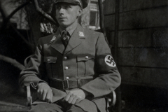SS-Angehöriger in Uniform mit Hakenkreuzarmband, sitzend